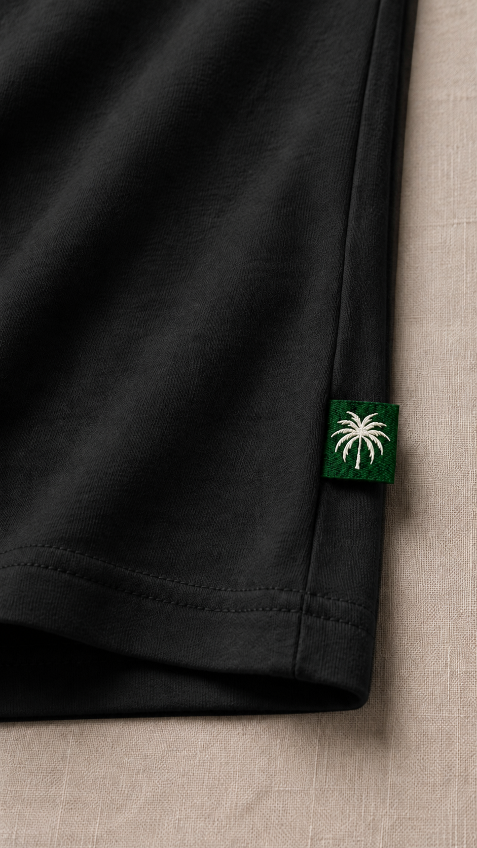 Dobladillo de la camiseta negro carbón con la etiqueta de la palma